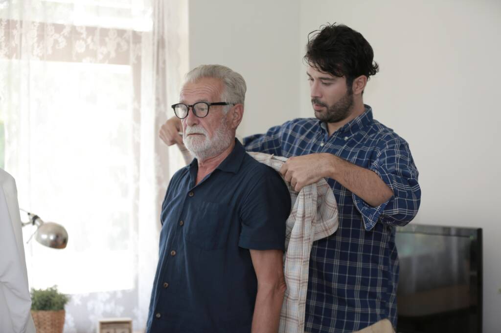 Adult hipster son and old senior father spend time together at home, take care dad. Father's day