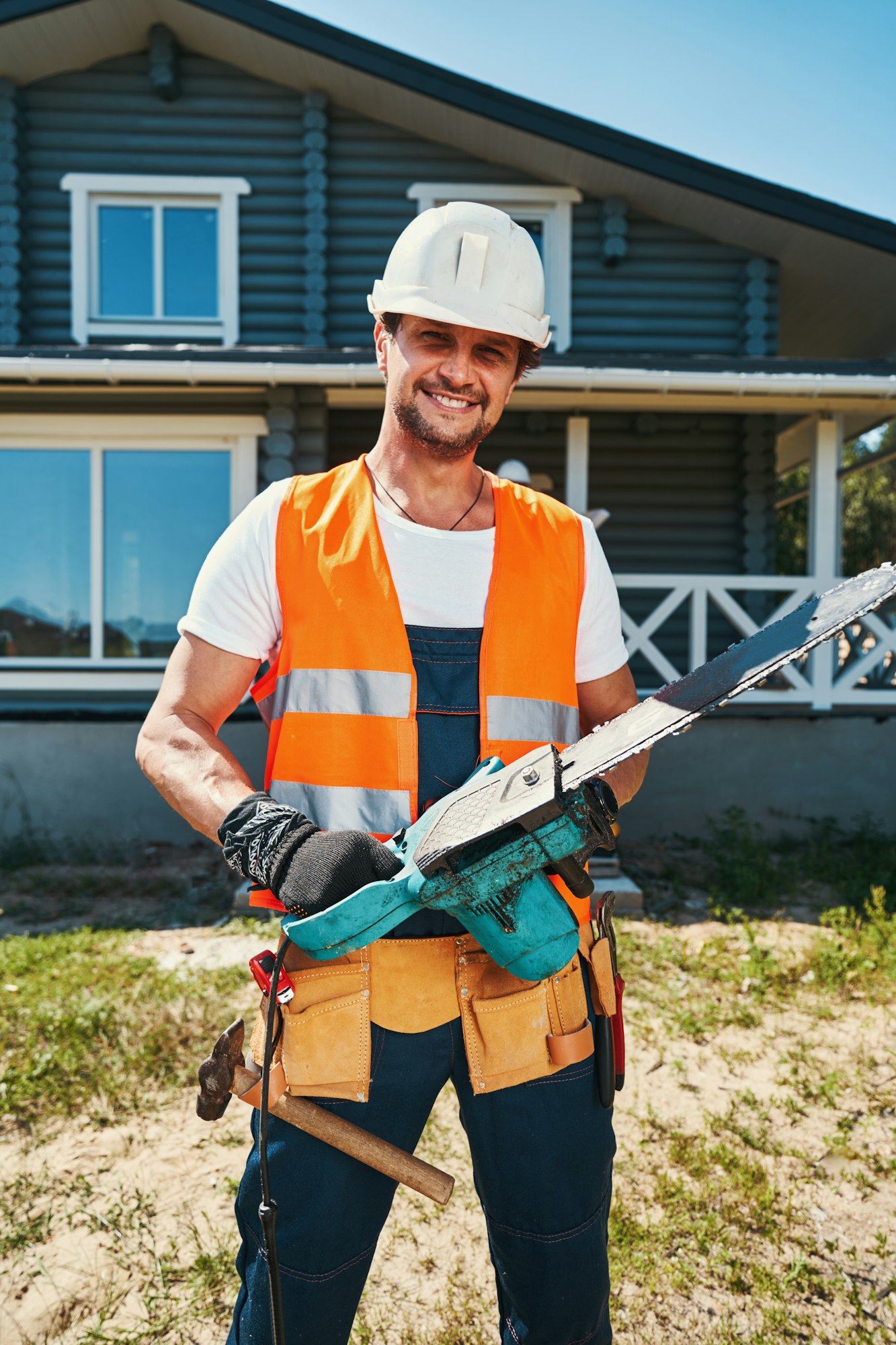 Happy construction worker standing with chainsaw in hands